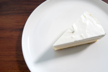 a piece of white cake on white dish. top view.
