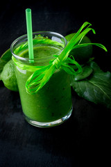 Green smoothie and ingredients for it on black wooden background. Diet. Detox. Healthy drink.