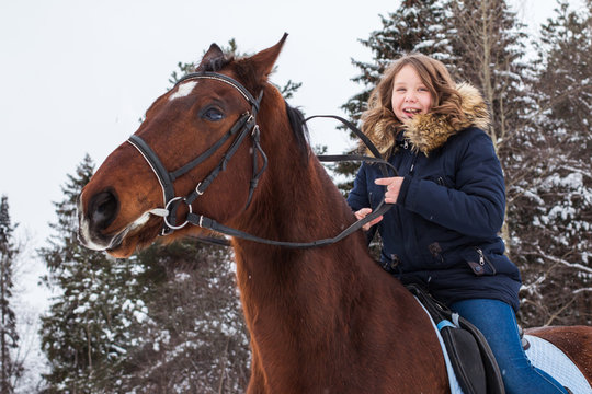 Girl teenager and big horse in a winter