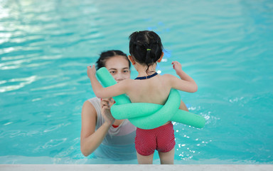 Close up mother teaching kid in swimming pool.