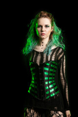 Woman in cosplay corset posing in studio with a green light from behind. Studio photo. Fashion and cosplay