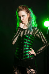 Beautiful Woman in cosplay corset posing in studio with a green light from behind. Studio photo. Fashion and cosplay