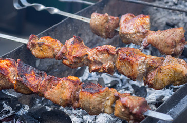 Pork meat cooking outdoor on skewers over smouldering carbon