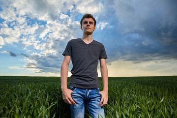 Teenager standing in a wheat field at sunset