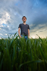 Naklejka na ściany i meble Teenager standing in a wheat field at sunset