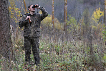 Man in camouflage and with guns in a forest belt on a spring hunt