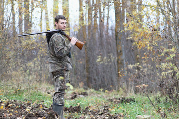 Man in camouflage and with guns in a forest belt on a spring hunt