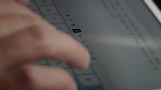Man typing text on electronic tablet using screen keyboard. Hands close-up.