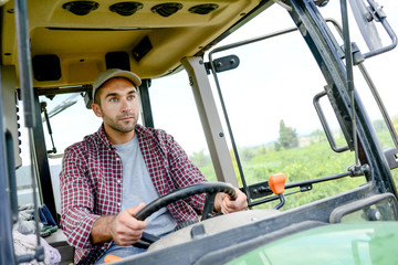 handsome young male farmer driving his tractor during harvest in the field countryside