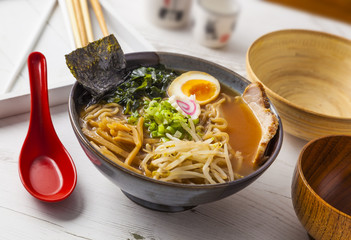 Miso Ramen Asian noodles with meat and egg in bowl on white wooden background.
