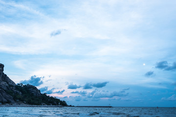 Rock dam and mountain on the sea with blue sky in the evening