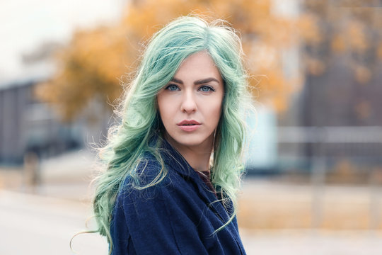 Trendy hairstyle ideas. Young woman with mint hair color on blurred background