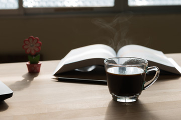 Black coffee cup with steam on office desk  table