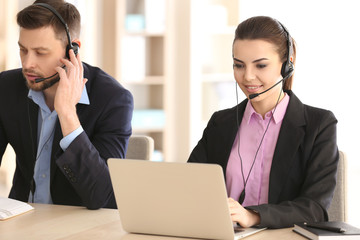 Young people with headsets working in office © Africa Studio