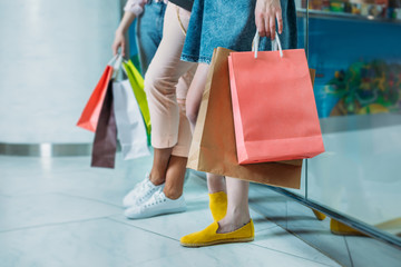 Cropped shot of young women with shopping bags standing in shopping mall, young girls shopping concept