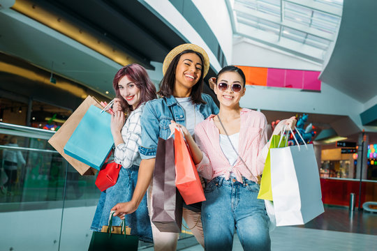 Happy stylish young women with shopping bags posing in shopping mall, young girls shopping concept