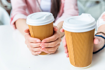 partial view of women holding cups of coffee in hands