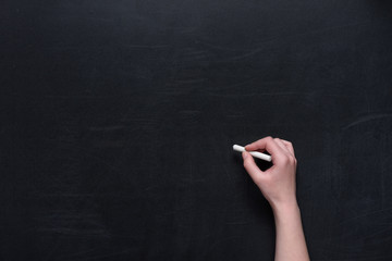 Naklejka premium human hand writing with piece of chalk on black chalkboard