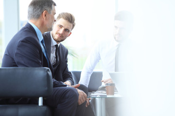 Mature businessman using digital tablet to discuss information with a younger colleague in a modern...