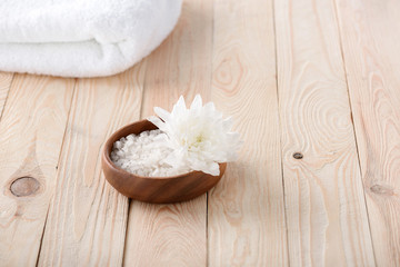 Obraz na płótnie Canvas Close-up view of beautiful white flower with sea salt and towel on wooden table