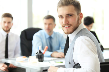 Happy smart business man with team mates discussing in the background.