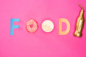 Top view of food word made from donuts and coffee isolated on pink. junk food background