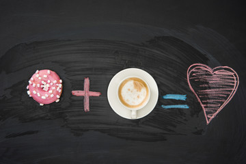 Food composition of donut with pink glaze and cup of coffee on black surface. donuts and coffee concept