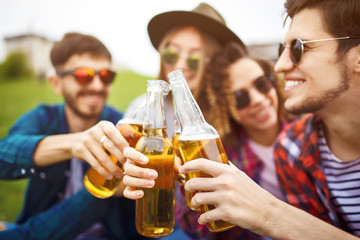 Group of friends enjoying party.people are drinking beer and laughing
.The guy plays the guitar. Everyone has a great mood. Summer time. 
