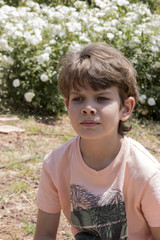 Close face of cute boy outdoor flowers in background