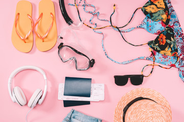 Group of women's casual outfits with gadgets and snorkeling equipment on pink background. Summer vacation concept