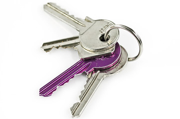 Four modern keys including one purple one on a chain isolated on a white surface.