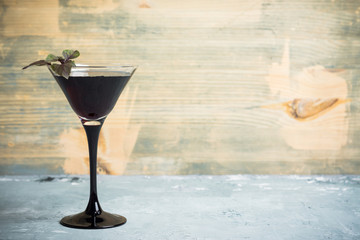 Black martini cocktail on the rustic background. Shallow depth of field.