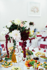 The vase with flowers and frame with number standing on the table