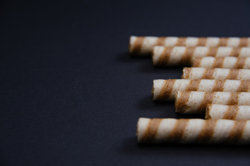Waffle rolls with cacao and chocolate. Fresh biscuits with chocolate. Text space for banner.
Waffle rolls in bowl on black background.