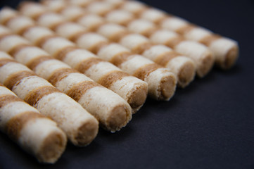 Waffle rolls with cacao and chocolate. Fresh biscuits with chocolate. Text space for banner.
Waffle rolls in bowl on black background.