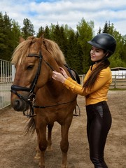 Young cheerful girl equestrian hugging her favorite red horse. Vertical image.