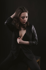 Seductive brunette woman in leather jacket in the dark