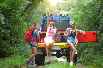 woman in group are enjoy traveling by sitting on the rack back of convertible car off-road in jungle
