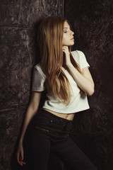Obraz premium Beautiful young woman with long blonde hair posing in dark room