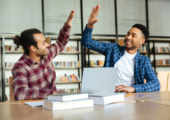 Two mixed race male students giving high five