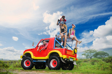 woman and man are traveling in group on the convertible car at field of lake