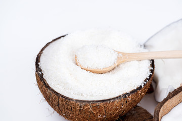 ripe organic coconut with sweet shavings with wooden spoon isolated on white