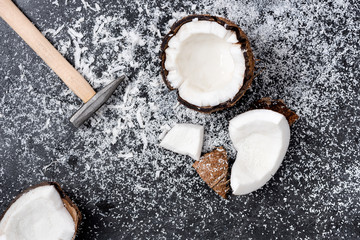 Top view of fresh broken coconut with shavings on black