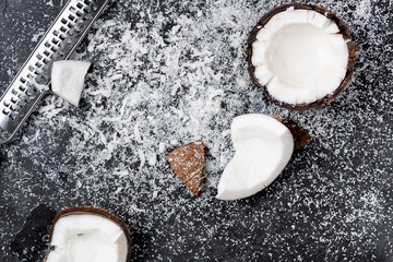 Top view of fresh broken coconut with shavings on black