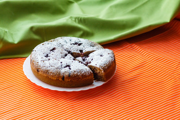 Homemade cake on a white plate on green and orange colored fabrics