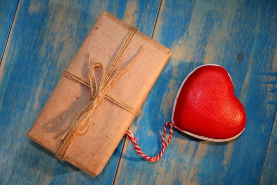 красное сердце и  подарок на синих деревянных досках       