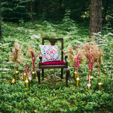 decorated wooden table served for two in the garden on grass on the riverbank. Boho and rustic style decoration with flowers, peacock feather, candles, clayware. Romantic date, table setting