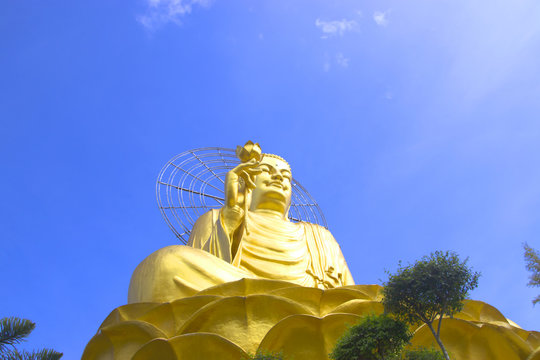big golden buddha with blue sky and clouds.