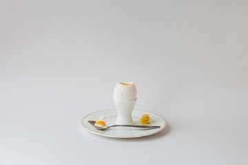 Beautiful Breakfast. Boiled white chicken egg on a white stand for eggs, white openwork plate, a silver teaspoon. Bright, white background. 