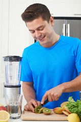 Male Athlete Making Juice Or Smoothie In Kitchen